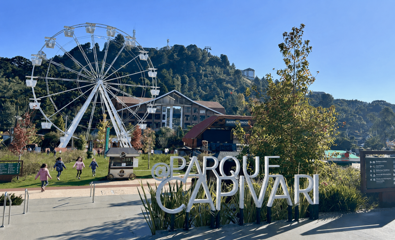 Crianças correndo no gramado do Parque Capivari em Campos do Jordão com teleférico ao fundo e montanhas da Serra da Mantiqueira