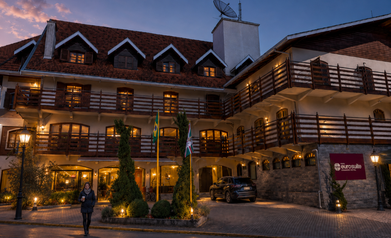 Hóspede saindo do hotel na Vila Capivari ao amanhecer com casaco de frio e café na mão, com a avenida vazia e luzes do calçadão ainda acesas em Campos do Jordão