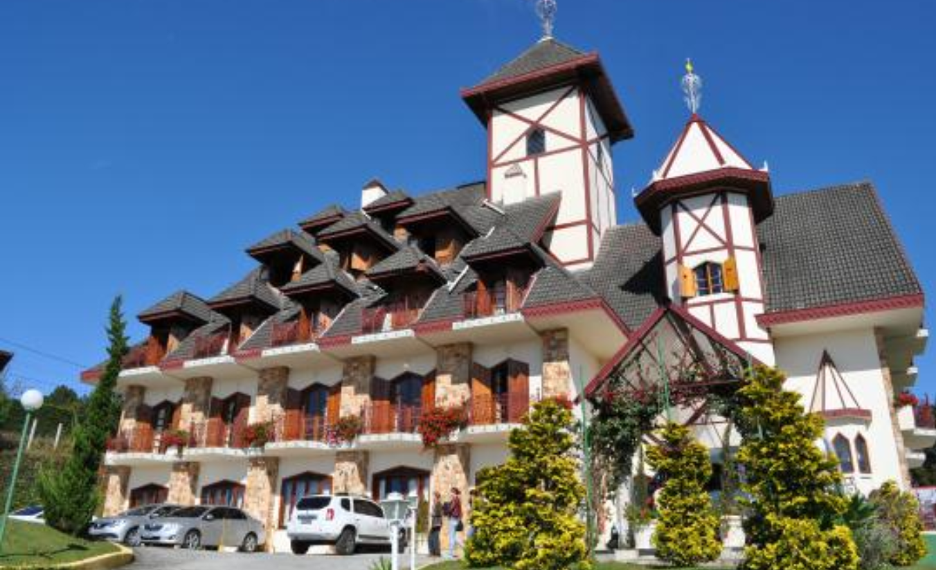 Hotel familiar na Vila Everest em Campos do Jordão com piscina aquecida coberta, montanhas ao fundo e crianças se divertindo em dia frio
