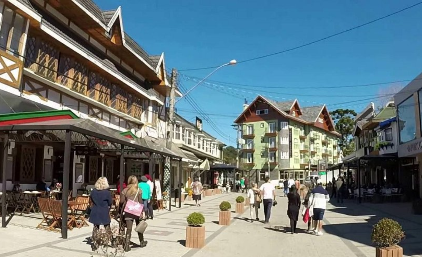 Rua movimentada da Vila Capivari em Campos do Jordão com lojas iluminadas, restaurantes e turistas caminhando