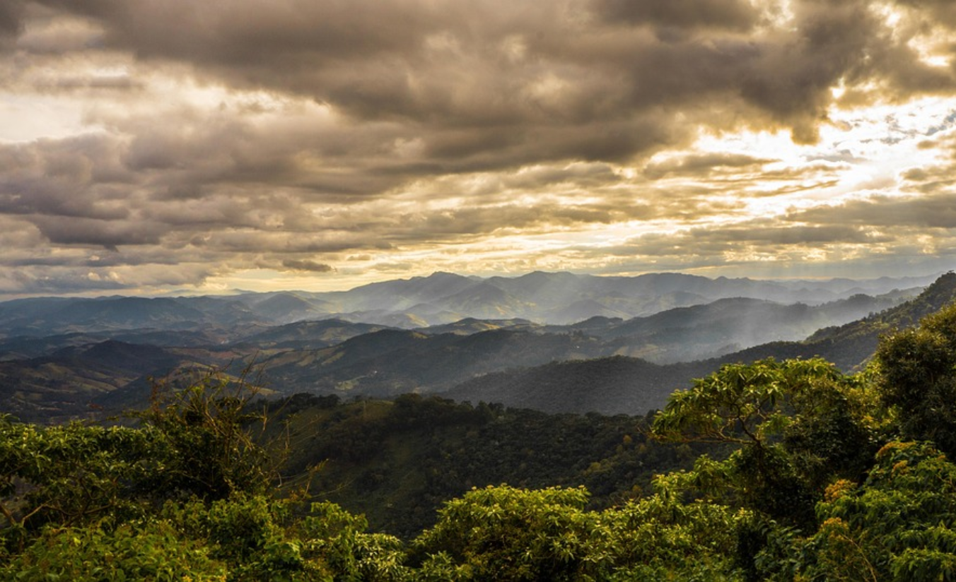 Vista da Serra da Mantiqueira ao entardecer a partir do centro de Campos do Jordão, com neblina suave sobre as montanhas