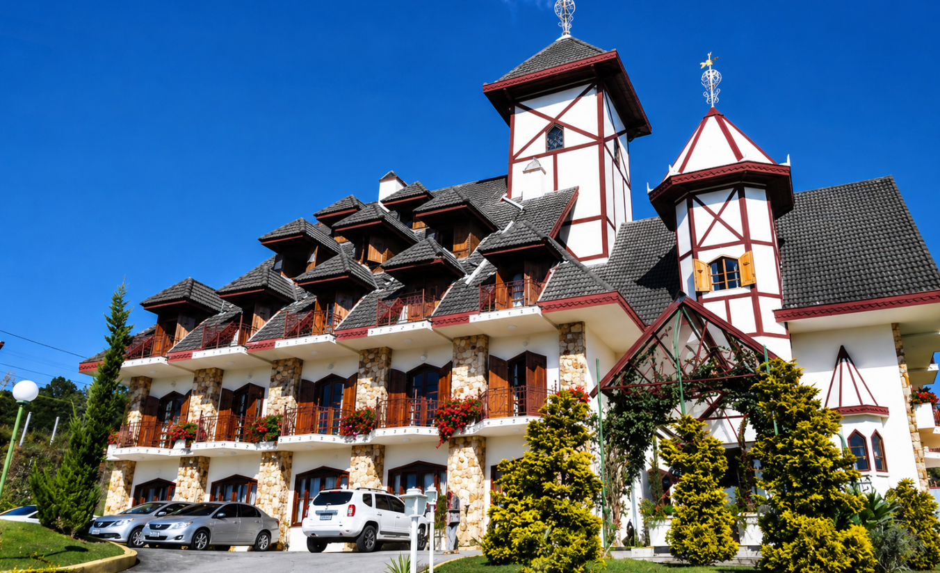 Vista externa do Hotel Nacional Inn Campos do Jordão na Vila Everest, com arquitetura de estilo europeu e jardim na entrada