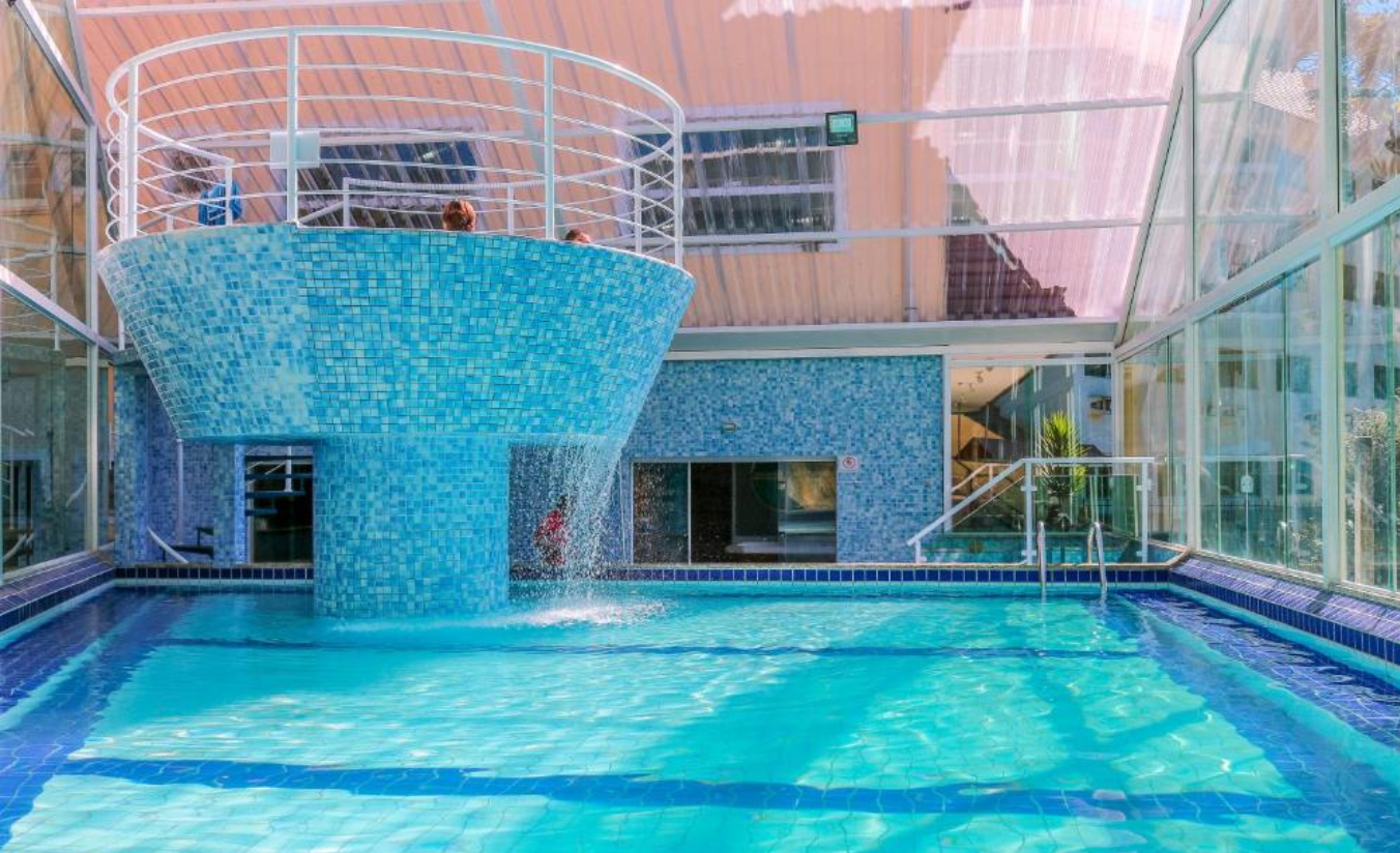 Piscina coberta e aquecida de hotel, cercada de estrutura de lazer para famílias no inverno serrano